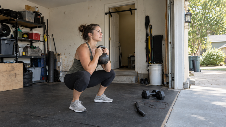 Beginner performing a kettlebell goblet squat in a modest home garage gym