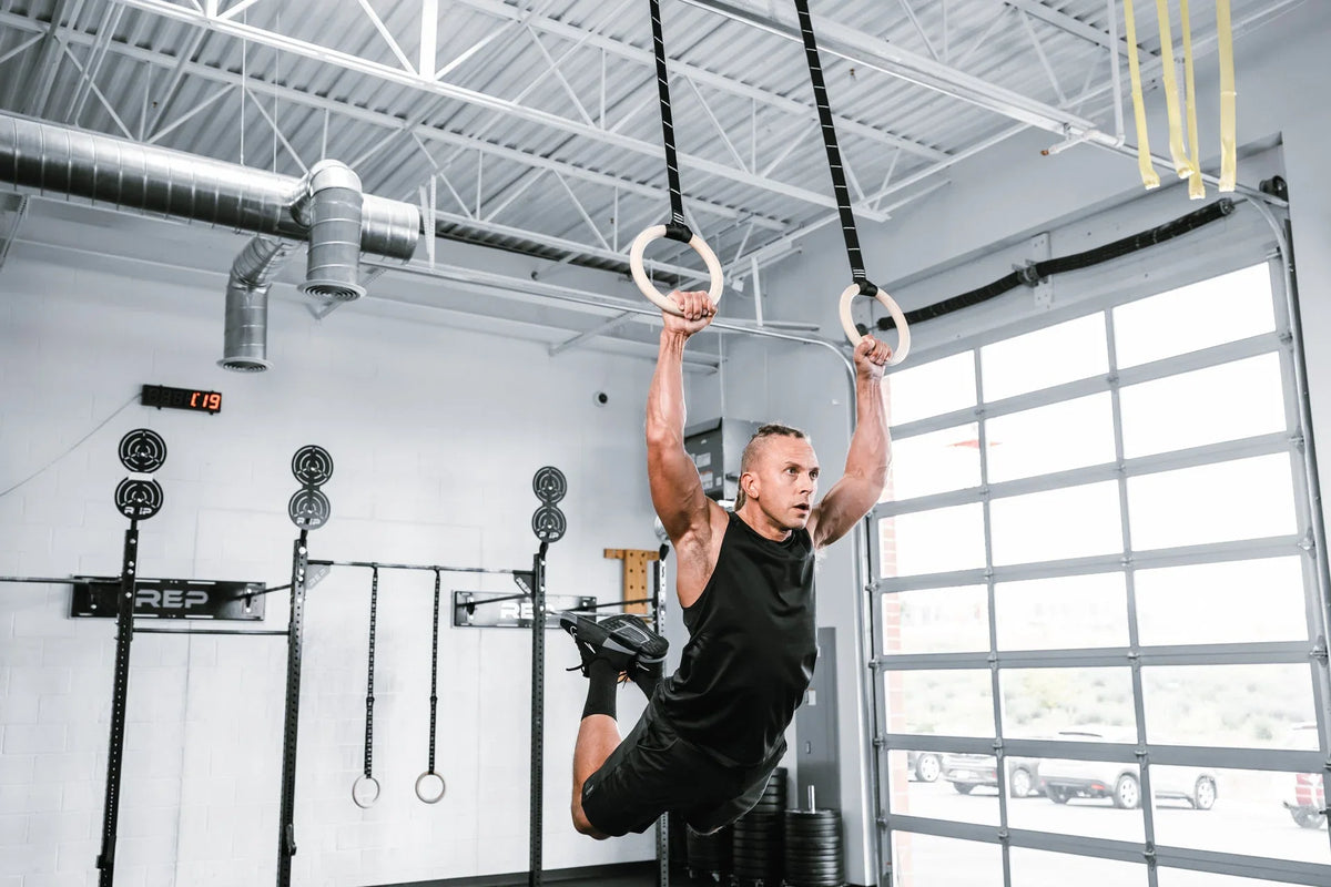 Athlete training on wooden REP rings in a bright gym; manufacturer photograph